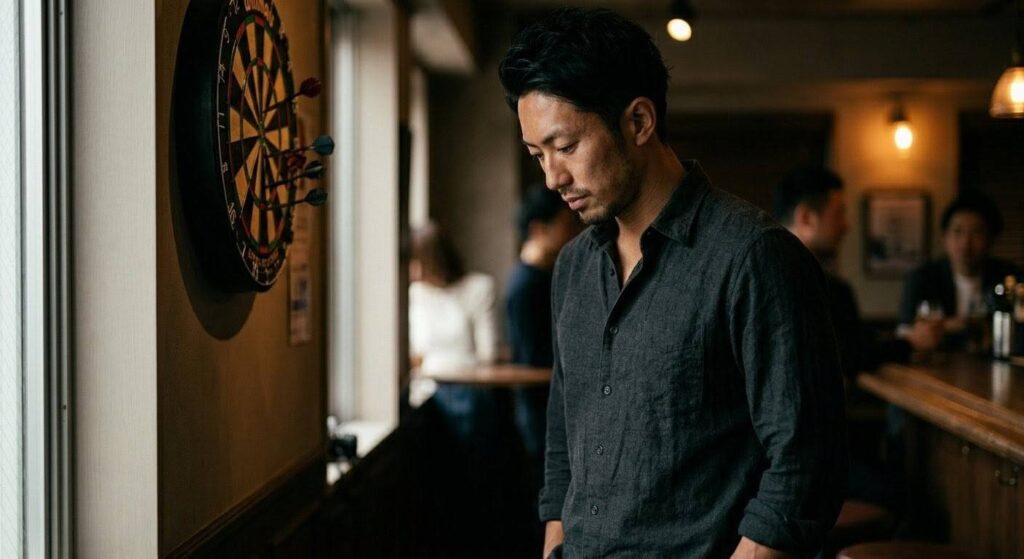 ダーツボードを背に、どこか虚無感を感じている日本人男性