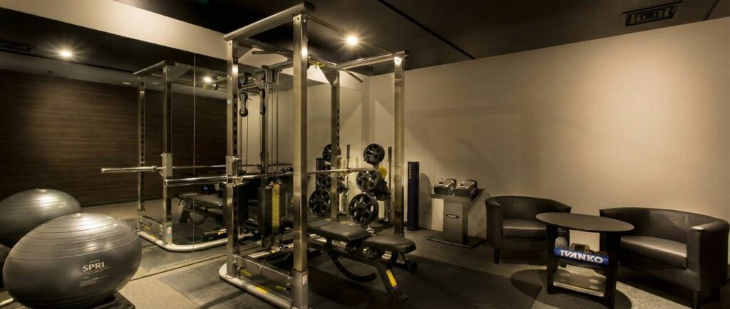 黒を基調とした高級感のあるライザップの完全個室トレーニングルーム。パワーラック、バーベル、ダンベル、バランスボールなどの充実したトレーニング設備と、休憩用の椅子とテーブルが設置されている。