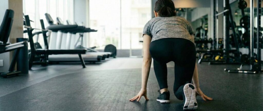 ジムのフロアで、走り出す準備をしている女性の背中